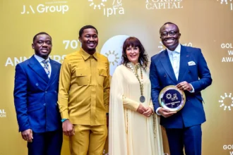 Bola Ray holding one of QNET's golden awards received at IPRA ceremony in Ghana